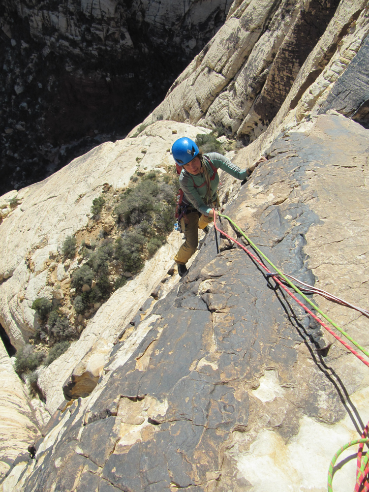 person climbing rocks with ropes attached